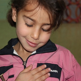 Syrian refugee girl with hand on heart